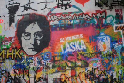 A photo of John Lennon surrounded by images of love and community, including his famous song "Imagine."