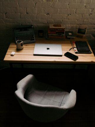 Warm-toned writing desk with laptop, books, and typewriter — a quiet creative space symbolizing mentorship and literary focus.