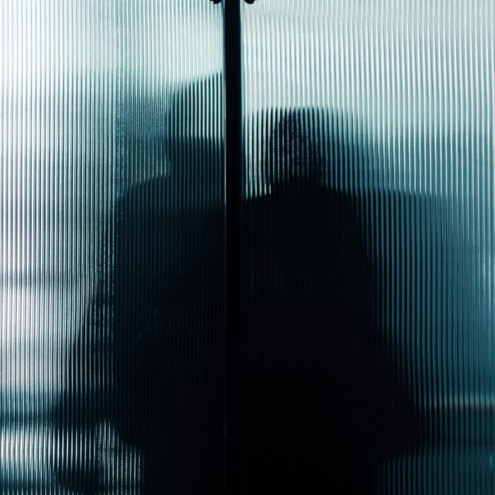 A solitary figure framed by window light, evoking hidden struggle and inner battles.