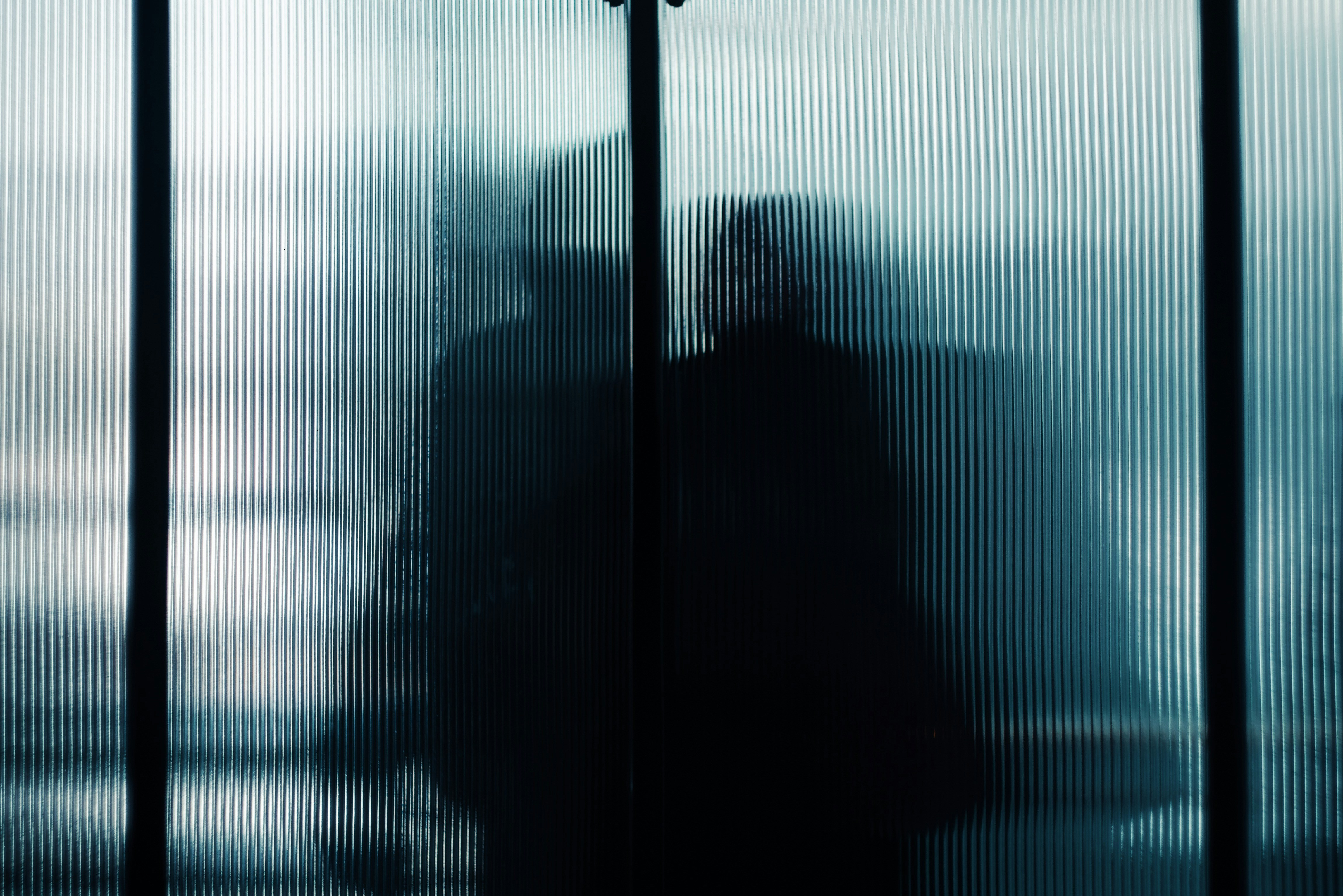 A solitary figure framed by window light, evoking hidden struggle and inner battles.