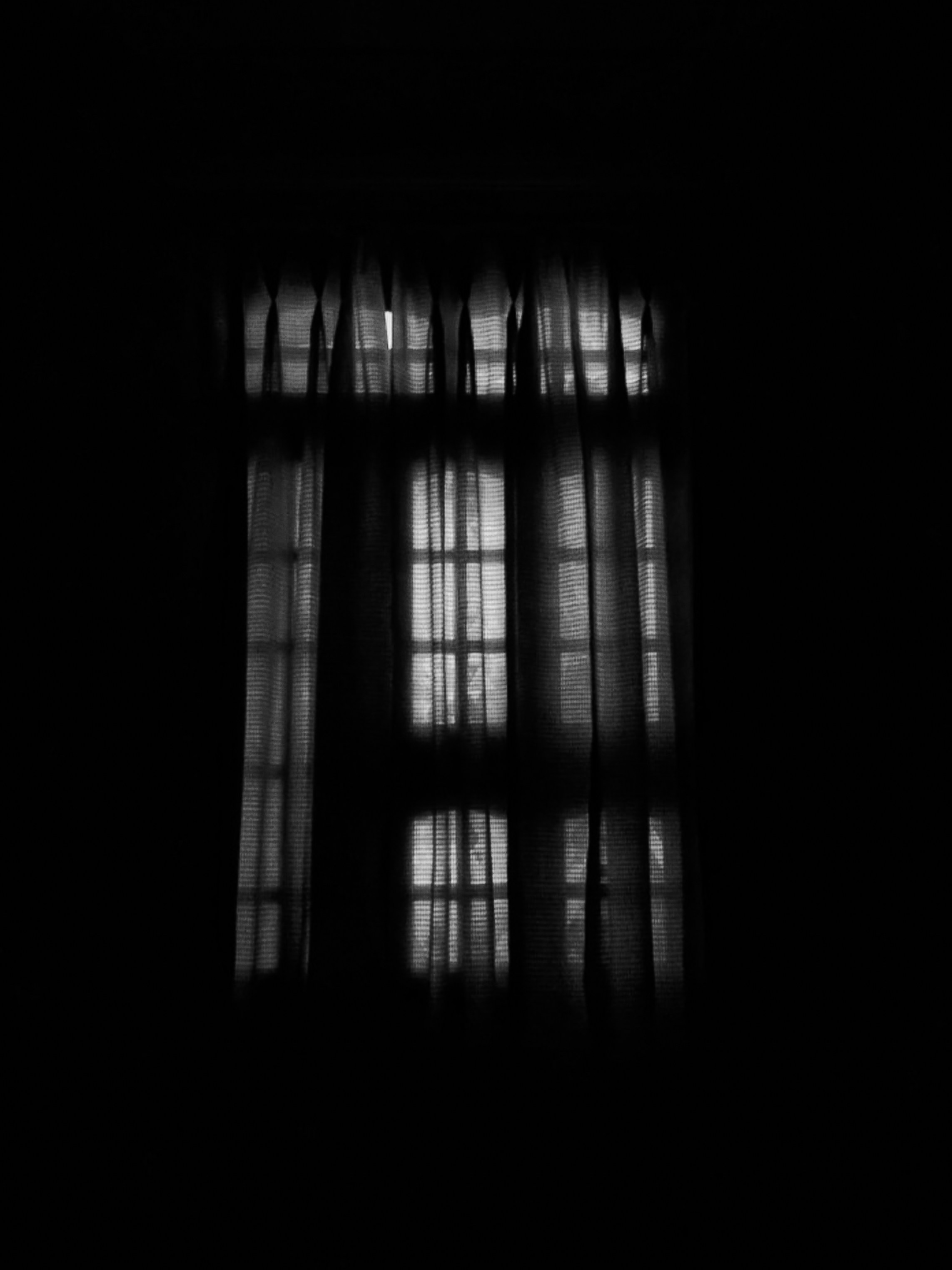 Barred window casting sharp shadows on a wall, evoking censorship and confinement