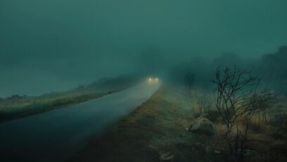 Hazy Middle Eastern coastline at dusk with distant ships on the horizon.