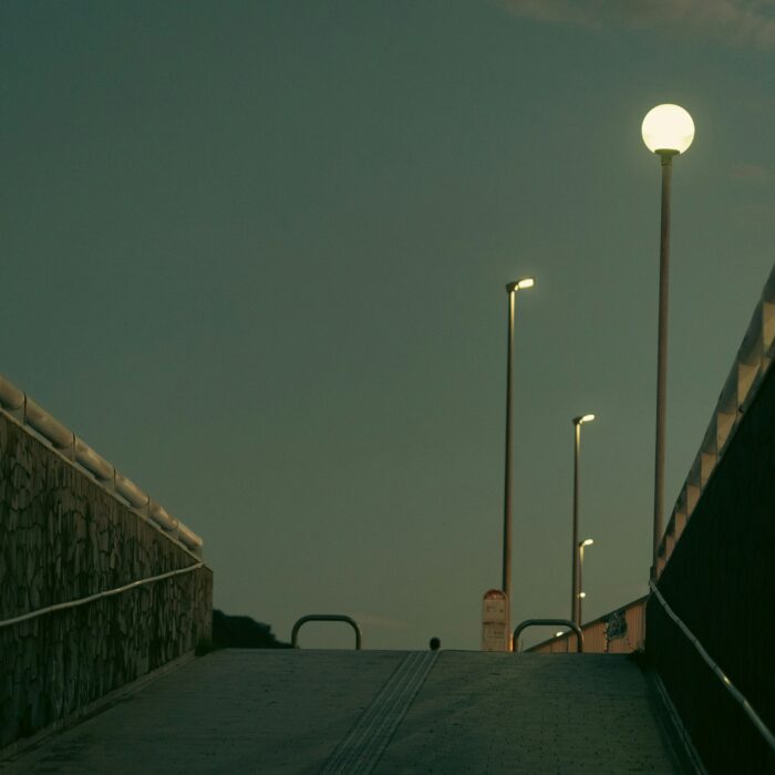 A dark bedroom lit by blue screen glow, evoking grief, virtual presence, and the emotional isolation of a digital afterlife.