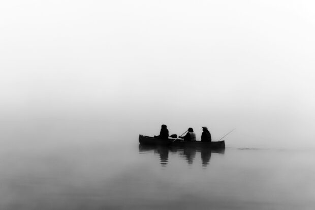 Image of people in a boat on a misty lake, searching through the cold and darkness.