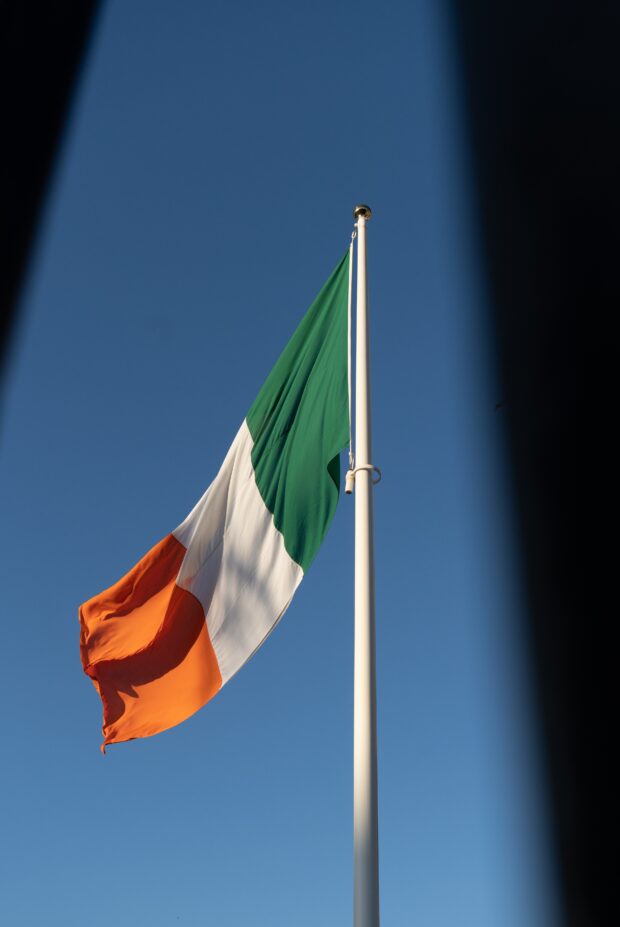 Image of the Irish flag against the backdrop of a clear blue sky.