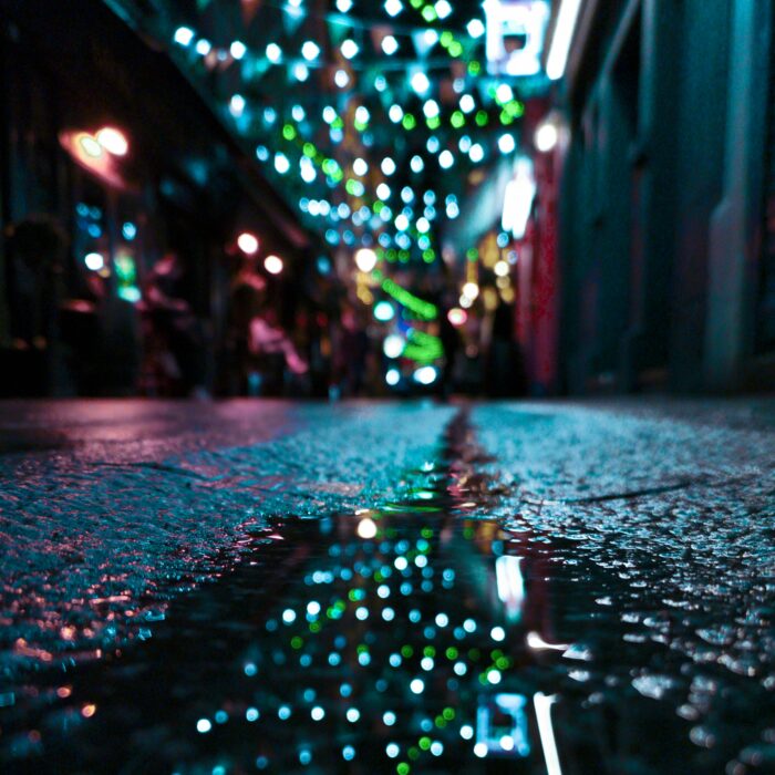 A rain-slicked British street glowing under orange lamplight.