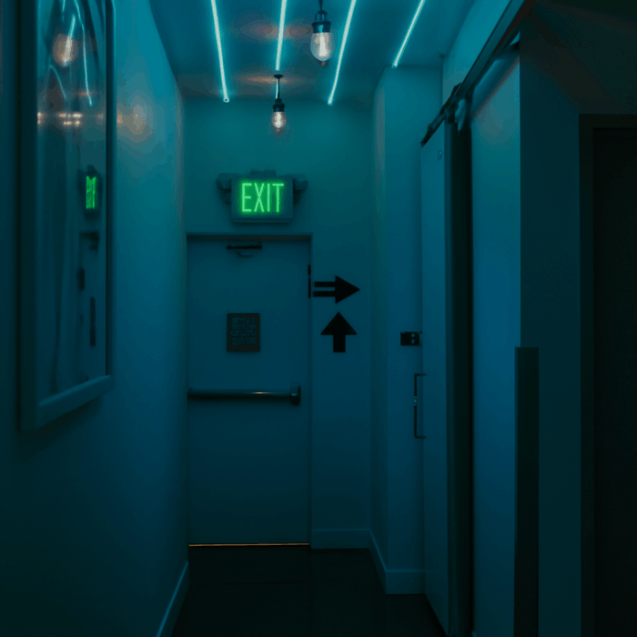 Cyan-lit office corridor with an EXIT sign at the end.
