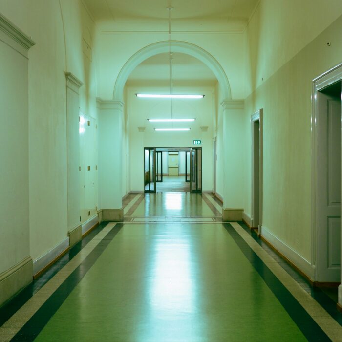 A dim interior framed by rain-streaked glass; a thin band of colour breaks the darkness like a fault line.