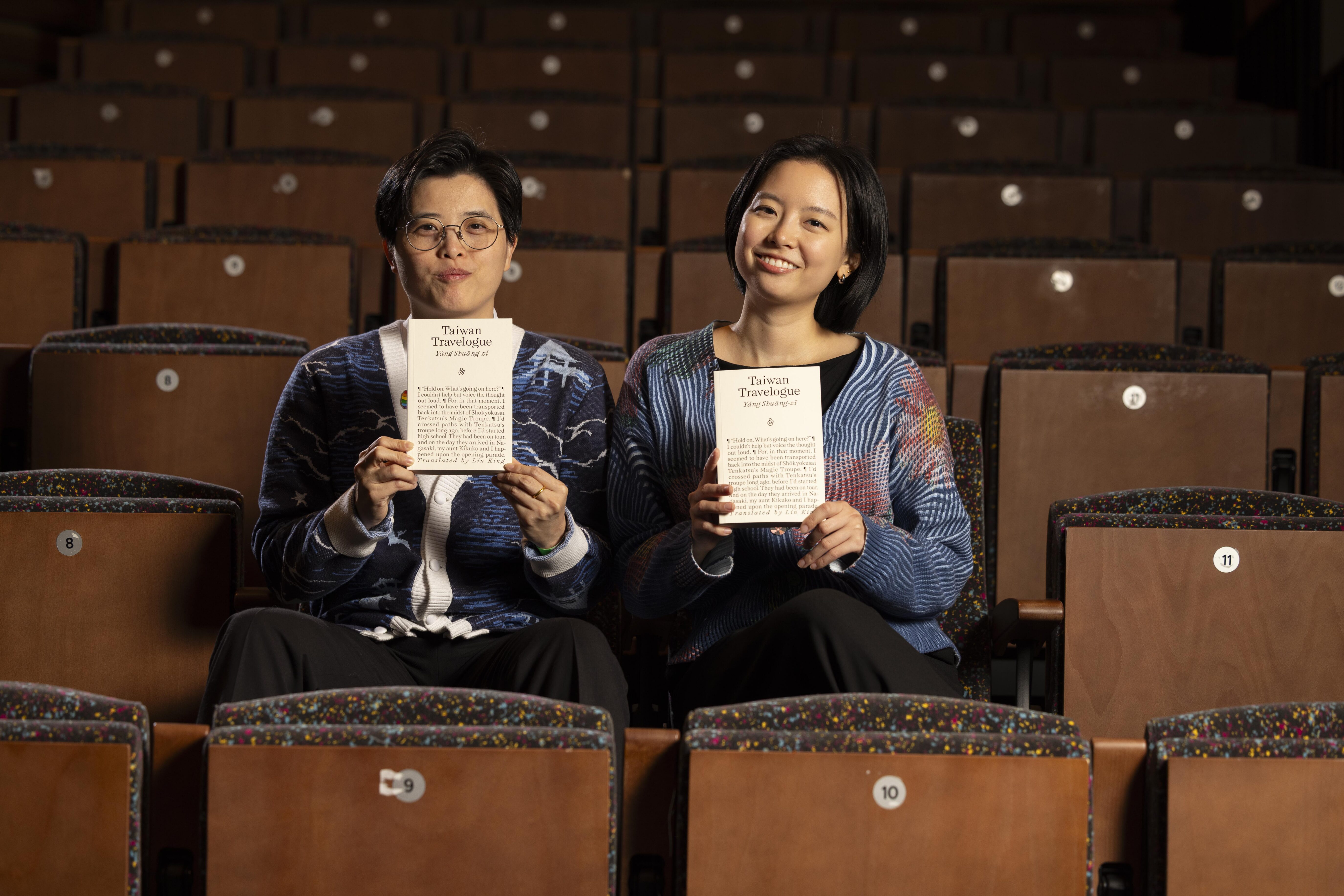 Yáng Shuāng-zǐ and Lin King seated in a theatre holding copies of Taiwan Travelogue