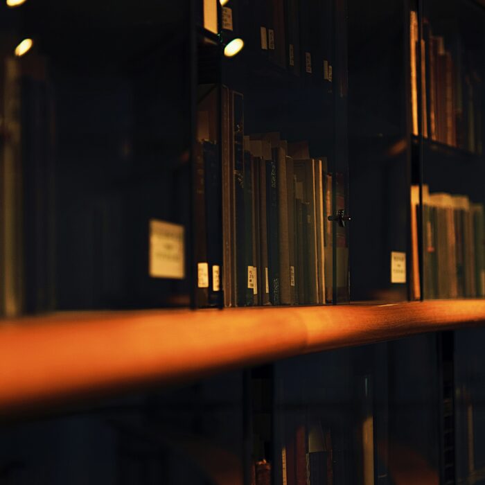 Books and records held behind glass in a dark archive setting