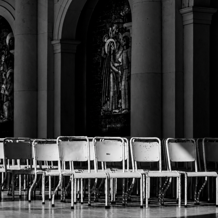 Rows of empty chairs in a dark ceremonial hall, suggesting public mourning and remembrance.