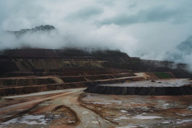 A terraced open quarry disappearing into low cloud and mountain mist.