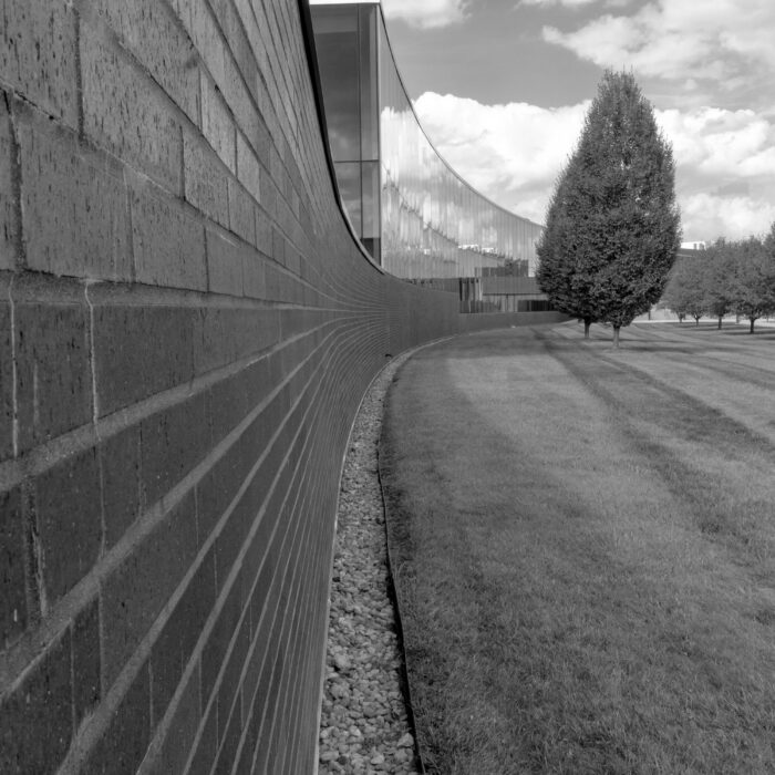 A black-and-white institutional building beside clipped grass and trees, evoking a controlled public space.
